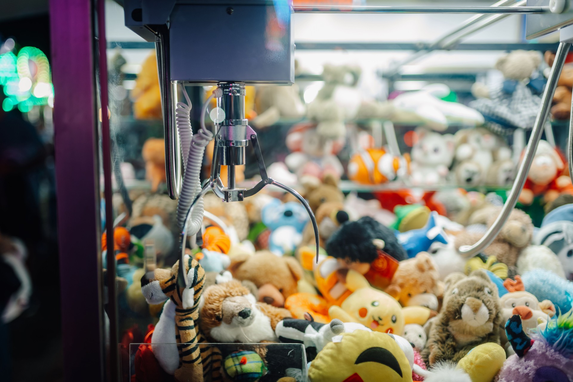Claw crane picking up plush toys in arcade game machine